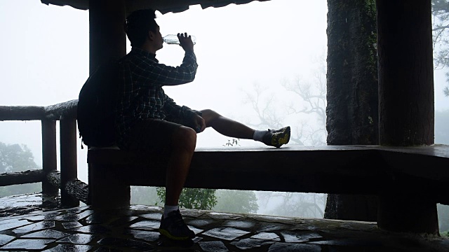 一名徒步旅行者在雨林的薄雾中喝水视频素材