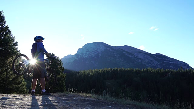 山地车在日出时骑到山顶，把自行车举过头顶视频素材