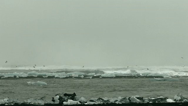 在冰岛南部的海滩上，海浪拍打着大块的冰。视频素材