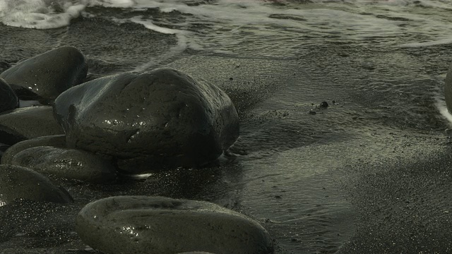 海浪滚过沙滩上的卵石的近景。视频素材