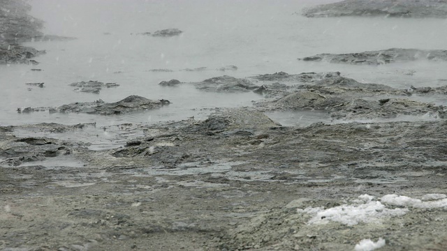 雪落在地热泥浆池上。视频素材