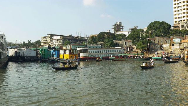 位于孟加拉国达卡的Sadarghat Launch Terminal是一个熙熙攘攘的客运枢纽，在这里，小木船出租车在巨大的钢轮渡旁划行视频素材