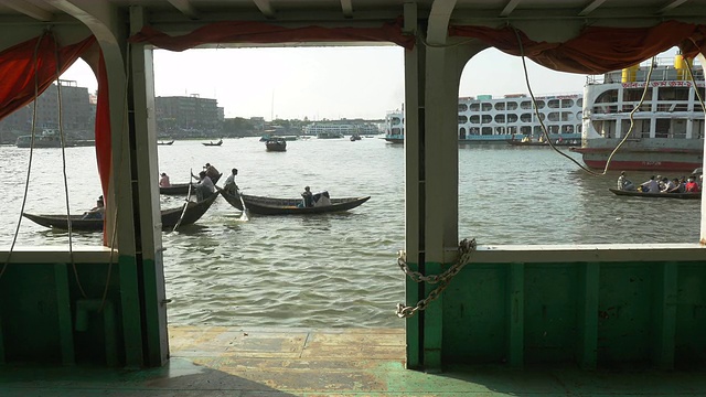 位于孟加拉国达卡的Sadarghat Launch Terminal是一个熙熙攘攘的客运枢纽，在这里，小木船出租车在巨大的钢轮渡旁划行视频素材