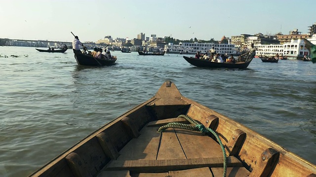 位于孟加拉国达卡的Sadarghat Launch Terminal是一个熙熙攘攘的客运枢纽，在这里，小木船出租车在巨大的钢轮渡旁划行视频素材