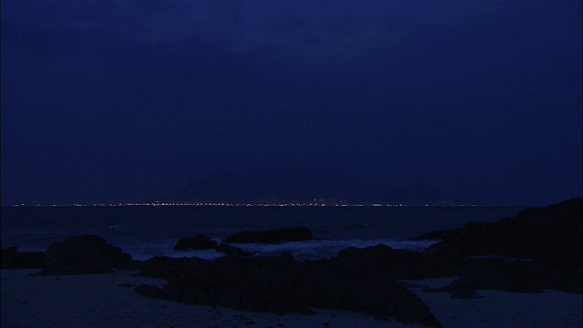 夜间波浪冲击着多岩石的海岸。视频素材