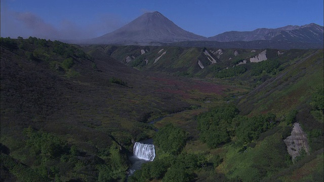 绿色山谷外的一座火山喷出火山灰。视频素材