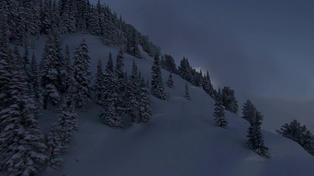 在瓦萨奇山脉覆盖着白雪、树木繁茂的山坡上，天空渐渐暗下来。视频素材