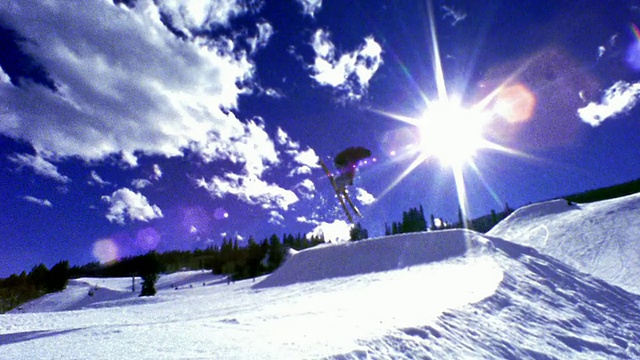 slow motion wide shot PAN man滑雪离开坡道，在空中飞行转弯+翻转/阿斯彭，科罗拉多视频素材