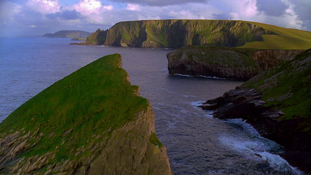 AERIAL over grass covered cliffs with green cliffs + ocean in background /爱尔兰视频素材