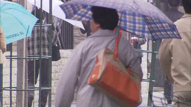 在中国上海，商务人士和学生在雨天带着雨伞。视频素材