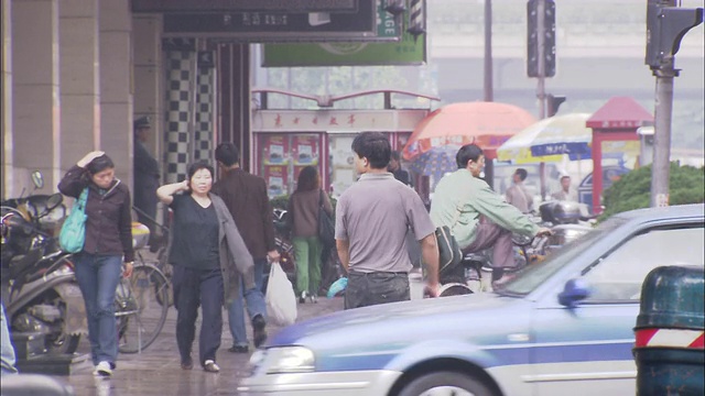 中国上海，行人撑着雨伞走过一条繁忙的街道。视频素材