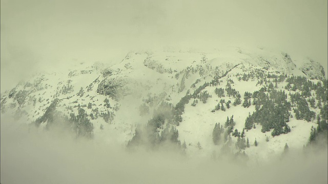 低空的云层环绕着白雪覆盖的阿拉斯加山脉。视频素材