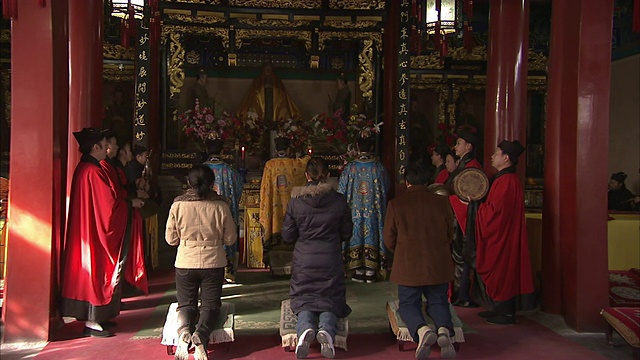 在北京白云观寺，朝拜者跪在祭坛前，而祭司则吟诵和演奏乐器。视频素材