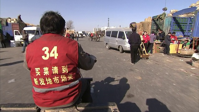 一个男人开着摩托车从行人和送货卡车旁边经过。视频素材