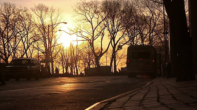 一辆公共汽车在街道上行驶，行人在夕阳下穿过街道。视频素材