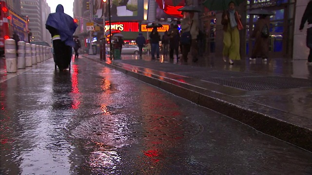 雨下着，行人走过店面。视频素材