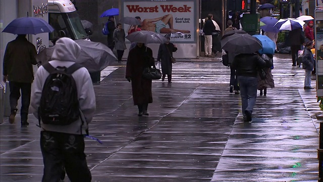 在纽约市的一个雨天，行人撑着雨伞穿过十字路口。视频素材