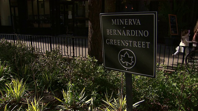 行人漫步在Minerva Bernardino Greenstreet的标志后面。视频素材