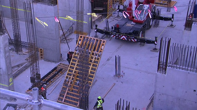 在一个大型建筑工地，建筑起重机降低了一段墙体。视频素材