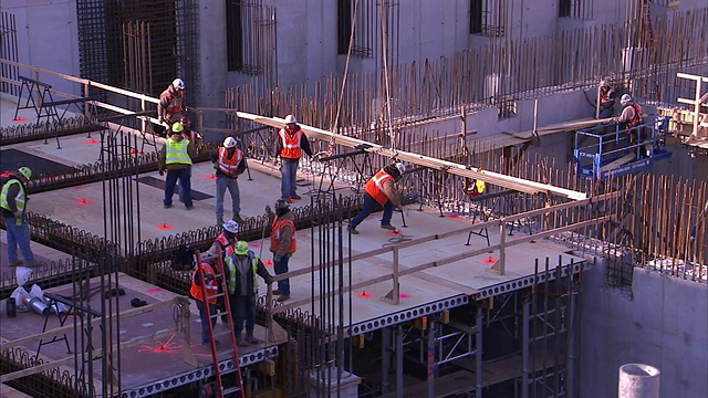 建筑工人在一个大型建筑工地建造高层建筑。视频素材