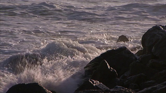 海浪拍打着多岩石的海岸上的巨石。视频素材