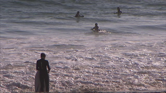 度假者在即将到来的海浪中冲浪和冲浪板。视频素材