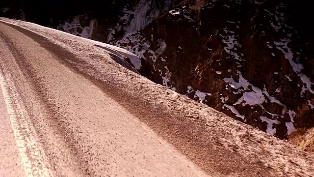 明亮的冬日阳光照耀着一条弯曲的山路。视频素材