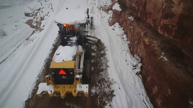 刨雪机在下雪时从山路上铲雪。视频素材