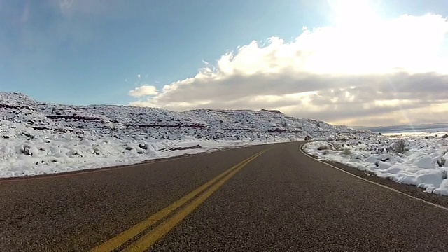 一条狭窄的道路穿过白雪皑皑的平原，延伸到遥远的地平线。视频素材