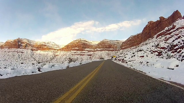 一条高速公路弯弯曲曲地穿过山区附近积雪覆盖的牧场。视频素材