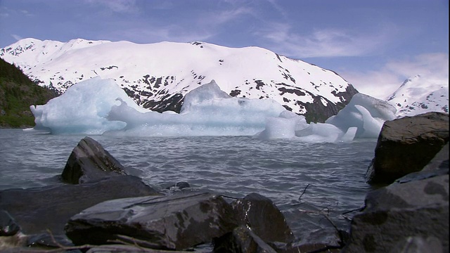 一条河流流过阿拉斯加的岩石河岸和雪山。视频素材