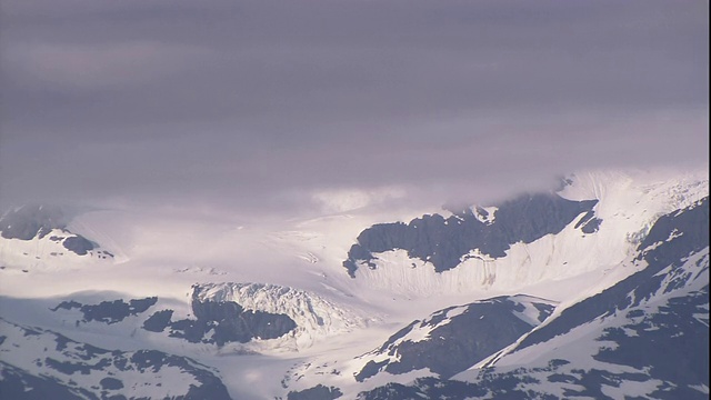 浓密的乌云笼罩着白雪皑皑的山峰。视频素材