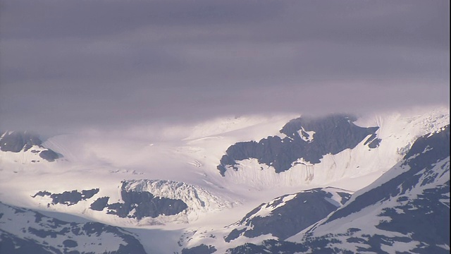 暴风雪的云层在白雪覆盖的山脉上空下降。视频素材