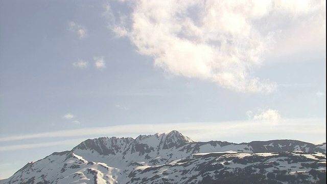 一朵朵白云迅速掠过崎岖的雪山。视频素材