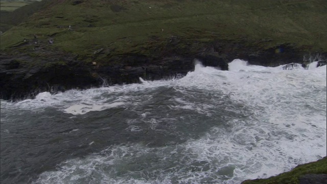 在英国一个渔村附近，海浪拍打着崎岖的海岸线。视频素材