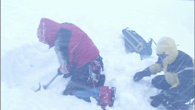 为了在暴风雪中求生，徒步旅行者在雪中挖了一个避难所。视频素材