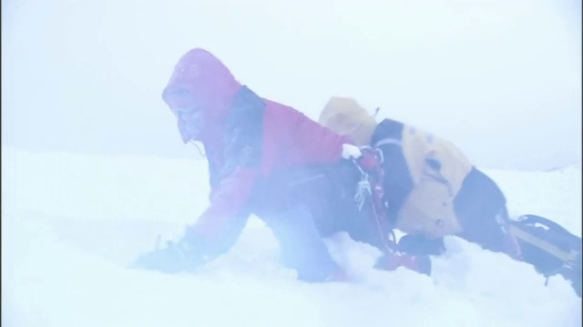 在暴风雪中艰难求生的徒步旅行者试图在雪中挖一个避难所。视频素材