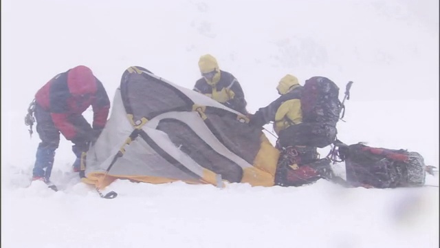 在暴风雪中徒步旅行者稳住帐篷。视频素材