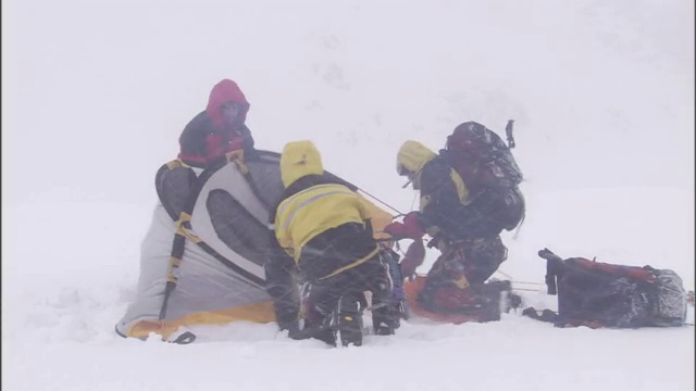 在暴风雪中徒步旅行者稳住帐篷。视频素材