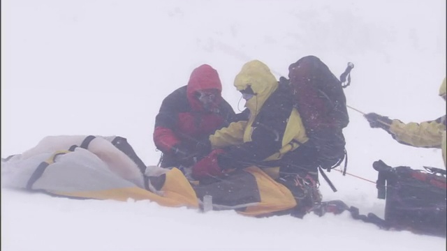 在暴风雪中，穿着冬季装备的徒步旅行者把帐篷打包好。视频素材