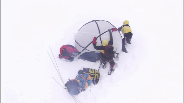 三名背包客在暴风雪中努力加固他们的帐篷。视频素材