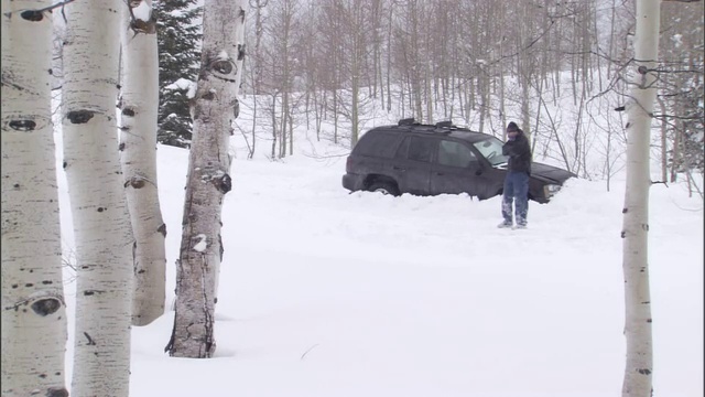 一名男子在暴风雪中艰难地离开一辆SUV。视频素材