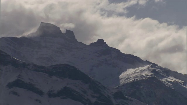 一团浓密的云飘过白雪皑皑的山峰。视频素材