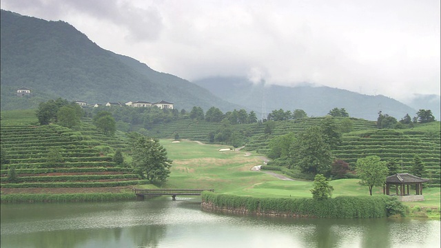 中国上海，一个多雾的日子里，梯田山环绕着富春度假村的一个湖边高尔夫球场。视频素材