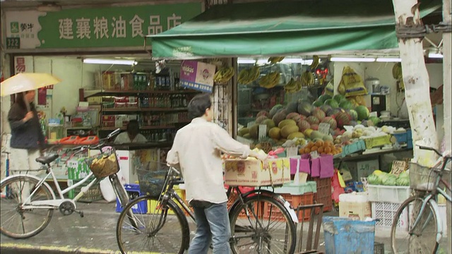 中国上海，一名修理工在一家农产品商店附近修理自行车。视频素材