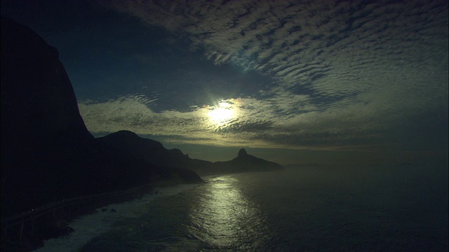 太阳反射在岩石海岸线附近的海洋上。视频素材