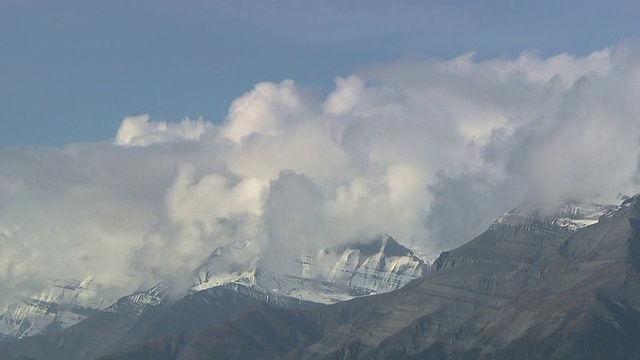 蓬松的云在雪山的山峰上翻腾。视频素材