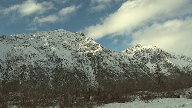 在阿拉斯加，云朵漂浮在白雪皑皑的高山和森林密布的山谷之上。视频素材