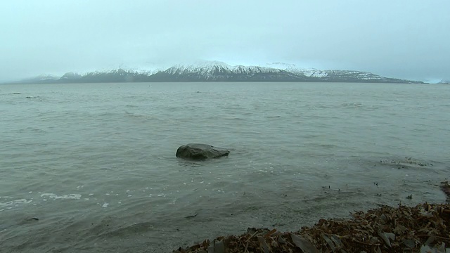 柔和的海浪拍打着多岩石的海滩。视频素材