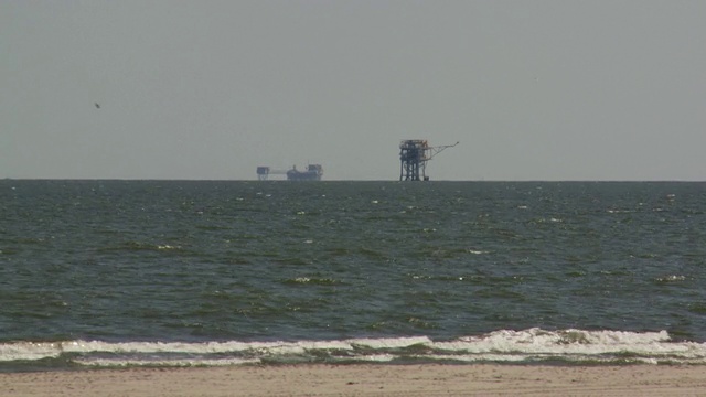 海浪从靠近近海石油钻井平台的墨西哥湾冲到海滩上。视频素材